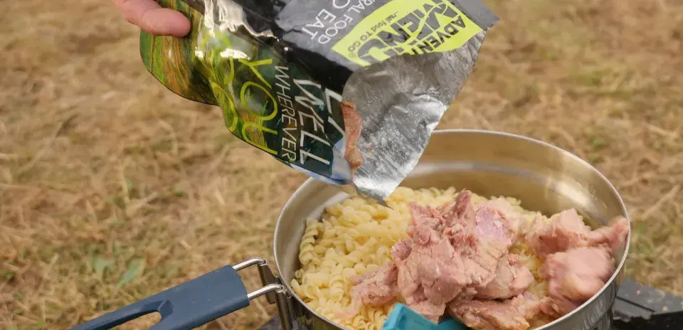 žena přendává sterilované jídlo adventure menu ze sáčku do hrnce