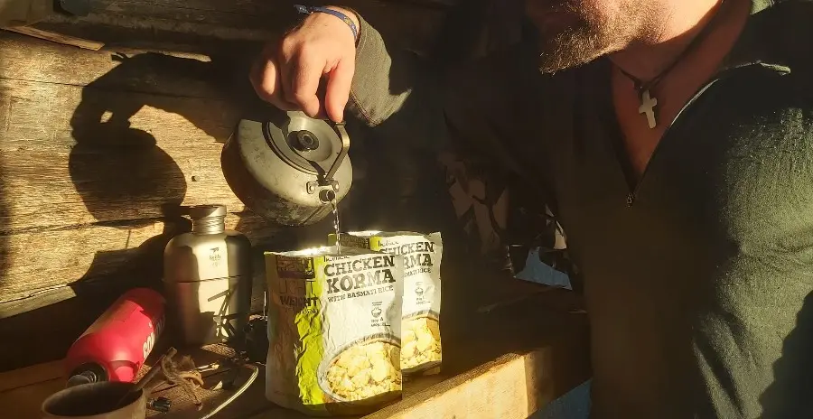 muž nalévá horkou vodu do sáčku s vakuově sušeným jídlem adventure menu