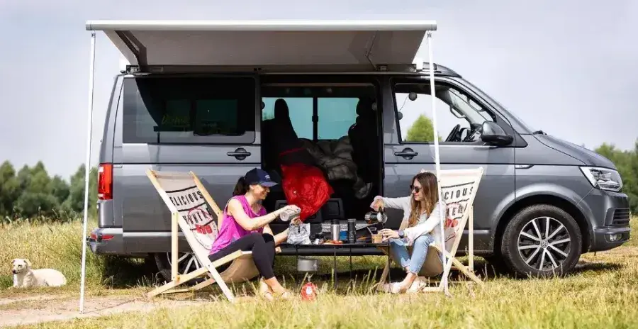 ženy sedí před karavanem v přírodě a připravují si lyofilizované jídlo