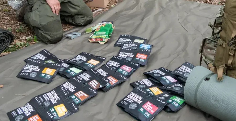 muž sedí na zemi před mnoha sáčky s jídlem tactical foodpack