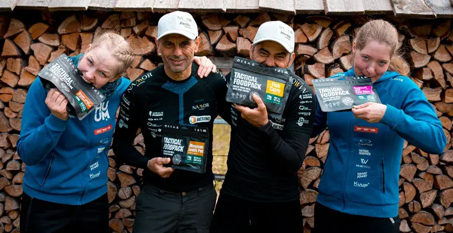 čtyři sportovci se objímají a drží v ruce balení s jídly tactical foodpack