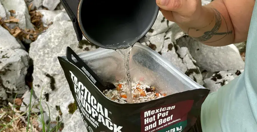 muž nalévá vodu do sáčku s lyofilizovaným jídlem