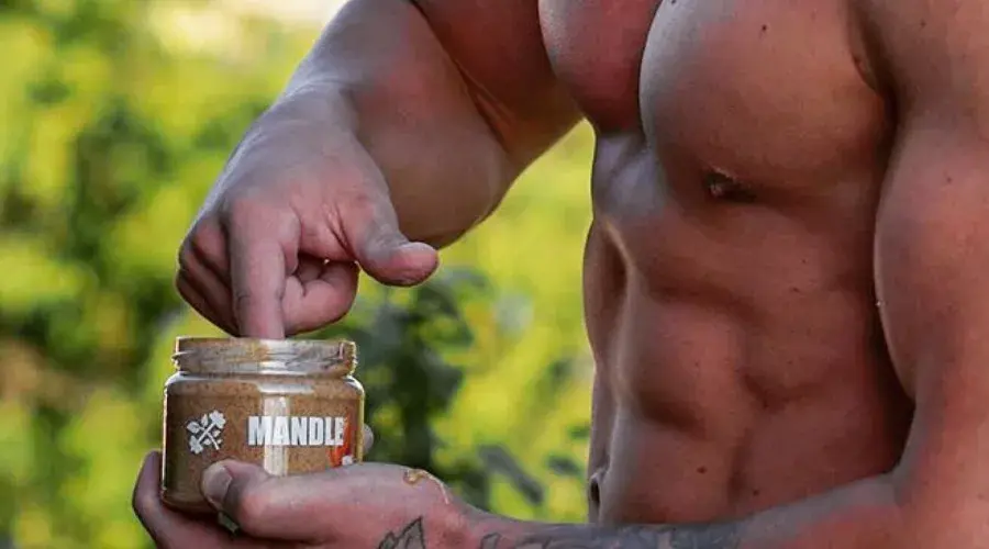 kulturista nabírá prstem ořechové máslo