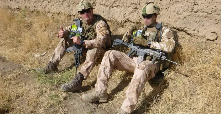 dva vojáci sedí na zemi a jí hotové mre armádní jídlo