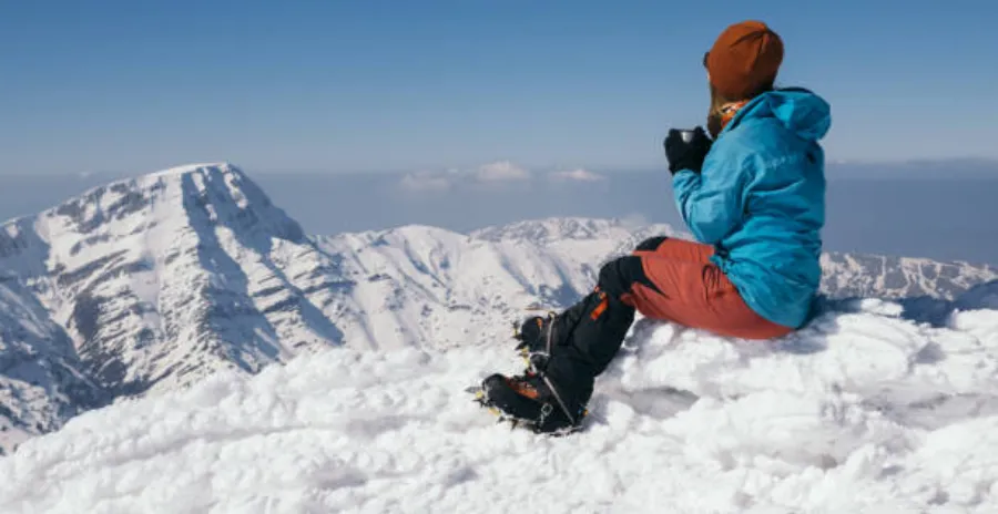 horolezkyně sedí na sněhu vysoko v horách a vychutnává si bezkofeinovou kávu dripit