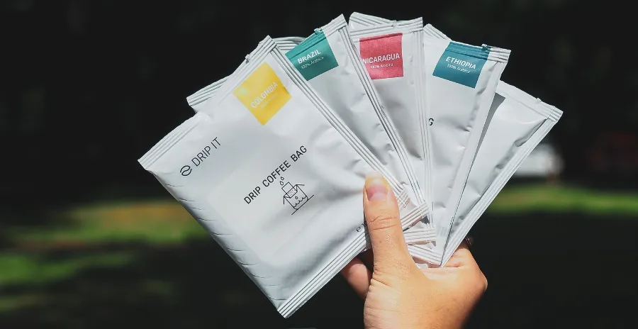 detail ruky, která drží několik různých filtrů s kávou dripit