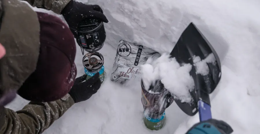 muž na sněhu zapaluje plynový vařič jetboil