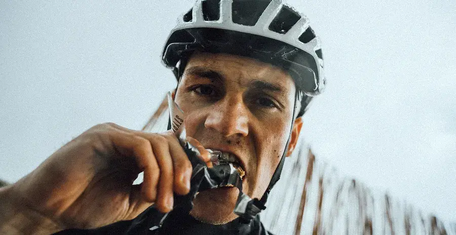 cyklista odpočívá a jí ořechovou tyčinku
