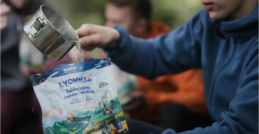 muž nalévá horkou vodu do sáčku s dehydrovaným jídlem lyommy